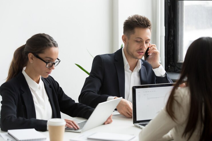 business Team members gathered around the table with their laptops, utilizing professional services automation to streamline project management and optimize resource allocation for enhanced efficiency.