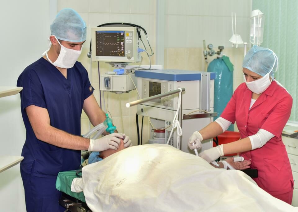 Врач и медсестра (ассистент) усыпляют пациента перед операцией.