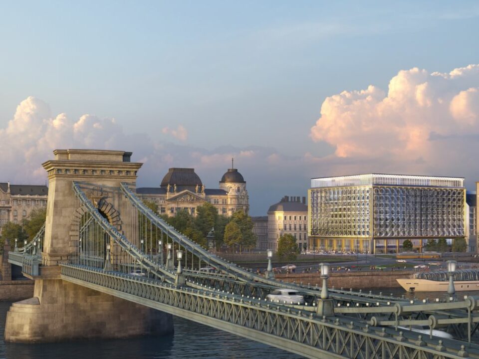 a bridge over water with buildings and trees SO/ Budapest hotel